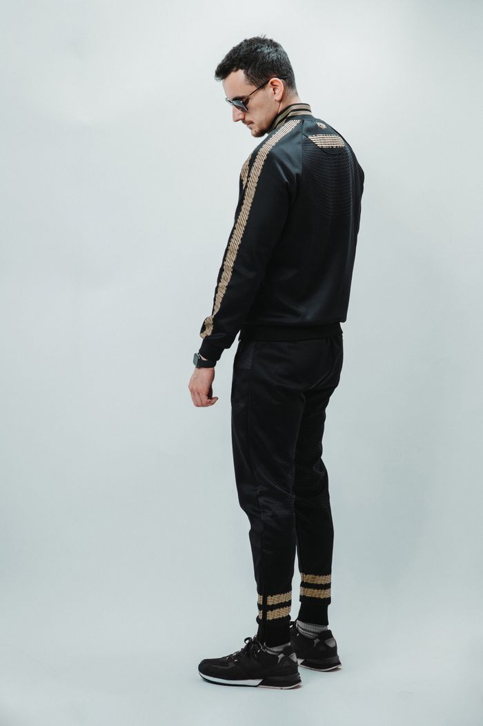 Fashionable young man in trendy sportswear, posing stylishly in a studio setting.