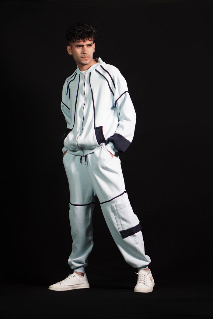 Portrait of a man in contemporary sportswear, standing confidently against a black background.